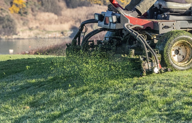 Large industrial mower cutting grass on sports field